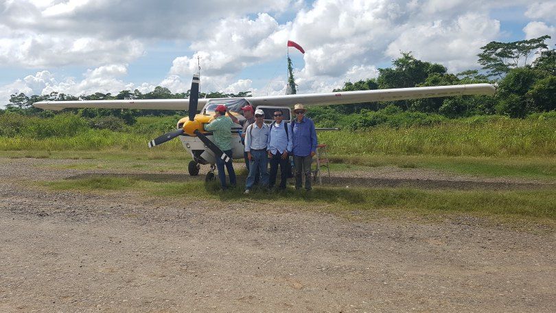 Equipo de investigadores frente a una avioneta en una pista de pasto