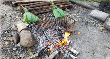 Paquetes envueltos en hojas sobre una parrilla con brasas