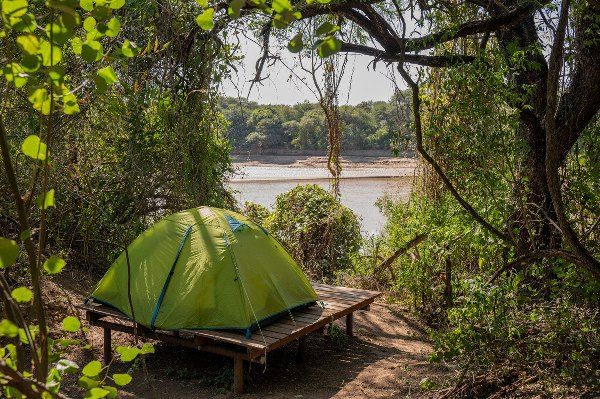 Carpa sobre una plataforma de madera junto al río